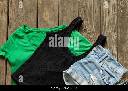 Damenbekleidung Shorts und T-Shirts in Grün und Schwarz auf Holzhintergrund Nahaufnahme Damenbekleidung Stockfoto