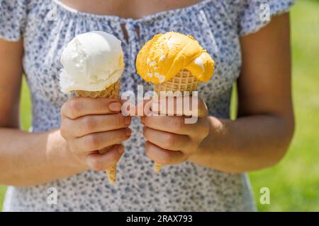 Frauenhände, die erfrischendes Eis in Waffelkonusen halten, schmecken mit einem Hauch von Zitronengeschmack Stockfoto
