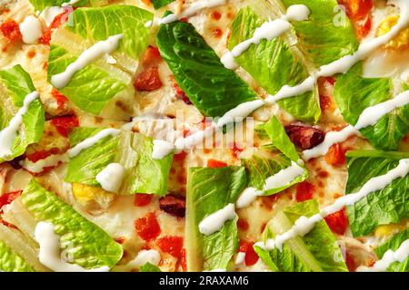 Frische Blätter von Romansalat auf Pizza mit Mozzarella und Joghurt, Hähnchenteile, Tomaten und rote Bohnen mit Sahne-Tee Stockfoto