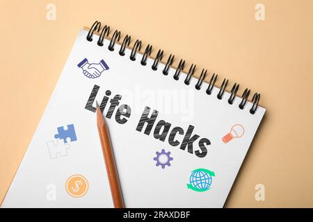 Notizbuch mit den Worten „Life Hacks“, Zeichnungen und Bleistift auf beigefarbenem Hintergrund, Draufsicht Stockfoto
