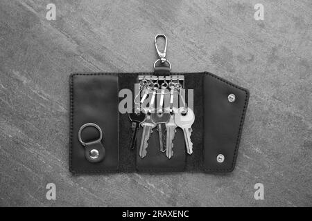 Lederhalter mit Schlüsseln auf grauem Tisch öffnen, Draufsicht Stockfoto