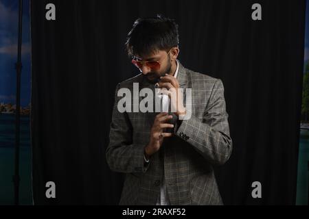Portrait glückliche, verkleidete Person im Anzug, die verschiedene Stimmungen zeigt. Unauffällige Aufnahme von bärtiger Bürokleidung. Schwarzer Hintergrund Stockfoto