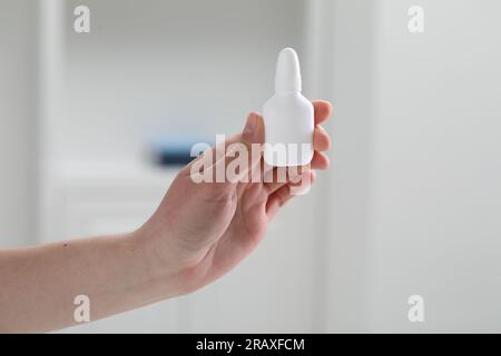 Frau, die Nasenspray-Flasche im Haus hält, Nahaufnahme Stockfoto