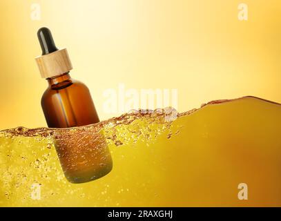 Flasche Kosmetikprodukt, die in ätherischem Öl vor goldfarbenem Hintergrund schwimmt Stockfoto