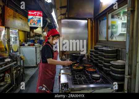 Seoul, Südkorea - 6. Juli 2023: Eine Frau, die Essen auf dem Namdaemun-Markt in Seoul zubereitet, ist der älteste Markt in Südkorea. Stockfoto