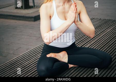 Halbkörperansicht von siddhasana Yoga und Hände in namaste Mudra oder Anjali Mudra in einem städtischen Raum Stockfoto