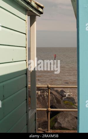 Zwischen zwei Strandhütten in Southwold, Suffolk. Großbritannien über den Felsen bis zum Horizont Stockfoto