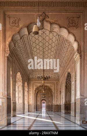 Wunderschöne Reihe von Bögen hinter der Fassade der antiken Badshahi-Moschee, erbaut vom mogul-Kaiser Aurangzeb, einem Wahrzeichen von Lahore, Punjab, Pakistan Stockfoto