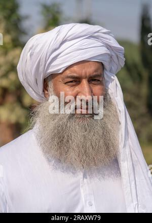 Außenporträt eines bärtigen Mannes mittleren Alters mit traditionellem weißen Kleid und Turban Stockfoto