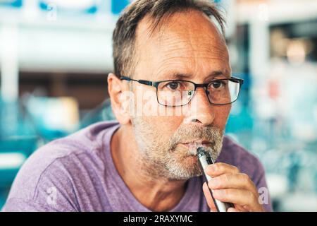 Ein Mann mittleren Alters, der elektronische Zigaretten raucht Stockfoto