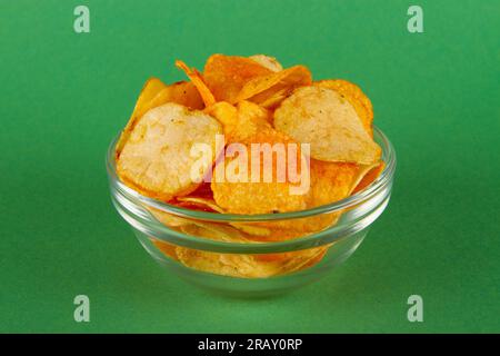 Kartoffelchips in Glasschüssel isoliert auf grünem Hintergrund. SEITENANSICHT Stockfoto