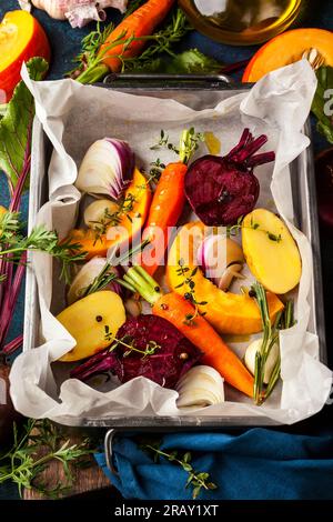 Zubereitung von geröstetem Gemüse mit Knoblauch und Kräutern auf dem Backblech. Herbst-Winter-Wurzelgemüse. Stockfoto
