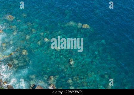 Blick auf die Felsen und das blaue, unberührte Meer mit klarem, transparentem Wasser. Ozeanhintergrund mit Kopierbereich Stockfoto