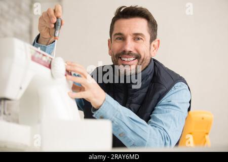 Mann, der eine industrielle Nähmaschine repariert Stockfoto