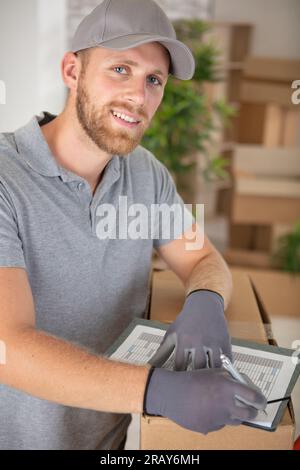 Porträt eines Umzugsagenten, der Artikel auf der Checkliste markiert Stockfoto