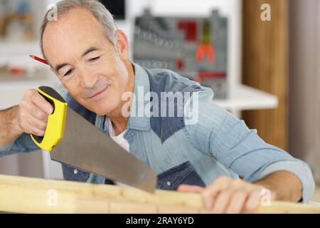 Älterer Mann sägen ein Protokoll Handsäge closeup Stockfoto