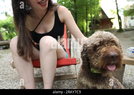 Entspannen und genießen Sie die Ruhe der Natur mit diesem Bild. Eine nicht wiedererkennbare Frau findet Trost, wenn sie Zeit mit ihrem niedlichen Hund in einem genießt Stockfoto