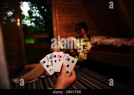 Erleben Sie die Spannung eines Kartenspiels mit diesem fesselnden Bild. Eine Nahaufnahme zeigt die Hand einer Frau, die eine Spielkarte hält und die zeigt Stockfoto