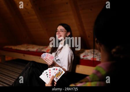 Erleben Sie die Spannung eines Kartenspiels mit diesem fesselnden Bild. Eine Nahaufnahme zeigt die Hand einer Frau, die eine Spielkarte hält und die zeigt Stockfoto