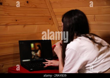 Erleben Sie das moderne Zeitalter der Online-Bildung, während eine junge, glückliche Frau im Bett mit ihrem Laptop arbeitet Stockfoto