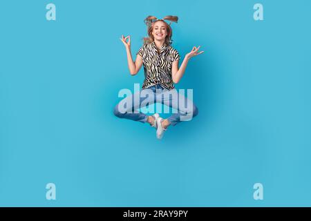 Großes Foto von Good Mood Woman gekleidete Zebrahemd Jeans Sneaker schwebend in Meditation Pose isoliert auf blauem Hintergrund Stockfoto
