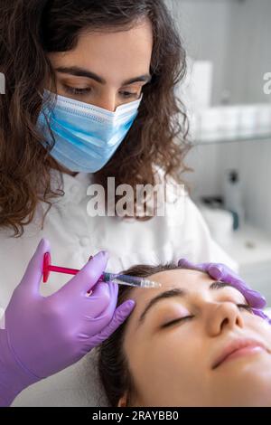 Junge Frau, die Haarmesotherapie-Injektionen von einem Facharzt erhält. Stockfoto