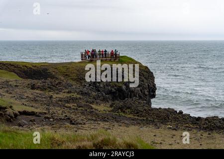 Arnarstapi, Island - 06.23.2023: Touristen am Aussichtspunkt der schwarzen Basaltklippen an den Arnarstapi-Klippen auf der Halbinsel Snaefellsnes, Island Stockfoto