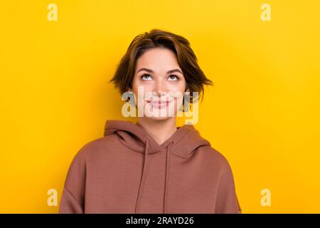 Foto jung wundert hübsche Dame Tricky Gesichtsausdruck Nachschlagen Modell tragen Hoodie Hemd isolierte gelbe Farbe Hintergrund Stockfoto