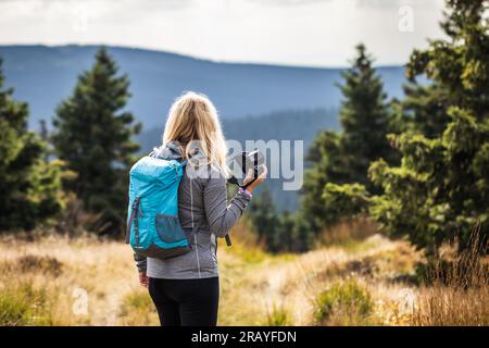 Frau Fotografin mit Rucksack und Kamera Wandern in den Bergen. Abenteuer in der Natur Stockfoto