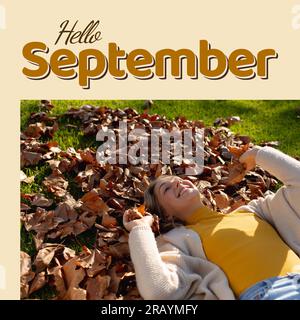 Hallo september Text in Browns with happy caucasian woman lying in Haufen von herbstlichen Blättern Stockfoto