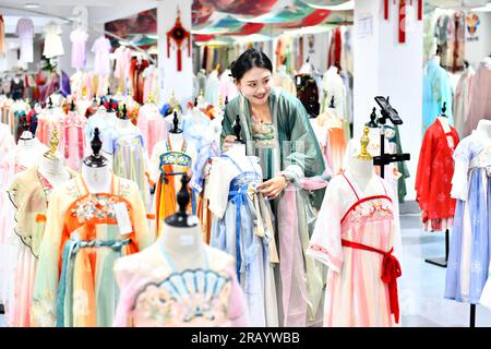 Caoxian, Chinas Provinz Shandong. 6. Juli 2023. Eine Frau wirbt für traditionelle chinesische Hanfu-Kleidung durch Livestreaming auf einem Hanfu-Stützpunkt in Caoxian County, Ostchina-Provinz Shandong, am 6. Juli 2023. Caoxian County hat in den letzten Jahren eine komplette Hanfu-Industriekette aufgebaut. Derzeit gibt es mehr als 2.100 mit Hanfu verbundene Unternehmen im Bezirk. Der Umsatz von Hanfu in Caoxian erreichte in der ersten Jahreshälfte fast 4 Milliarden Yuan (etwa 552 Millionen US-Dollar). Kredit: Guo Xulei/Xinhua/Alamy Live News Stockfoto