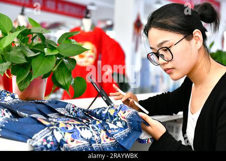 Caoxian, Chinas Provinz Shandong. 6. Juli 2023. Designer Liang Li arbeitet an einem Stickereimuster traditioneller chinesischer Hanfu-Kleidung auf einem Hanfu-Stützpunkt in Caoxian County, Ost-Chinas Provinz Shandong, am 6. Juli 2023. Caoxian County hat in den letzten Jahren eine komplette Hanfu-Industriekette aufgebaut. Derzeit gibt es mehr als 2.100 mit Hanfu verbundene Unternehmen im Bezirk. Der Umsatz von Hanfu in Caoxian erreichte in der ersten Jahreshälfte fast 4 Milliarden Yuan (etwa 552 Millionen US-Dollar). Kredit: Guo Xulei/Xinhua/Alamy Live News Stockfoto