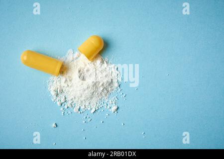 Streupulver aus Gelatine Kapseln Pillen, öffnen oral Medizin gefüllt mit Pulver auf blauem Hintergrund, direkt von oben genommen mit Kopie sp Stockfoto