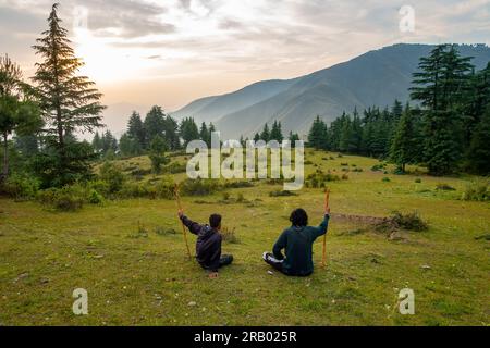 28. Juni 2023, Nagthat, Uttarakhand, Indien. Wanderer tauchen ein in einen atemberaubenden Sonnenuntergang, umgeben von malerischen Hügeln, Wiesen und dem majestätischen Er Stockfoto