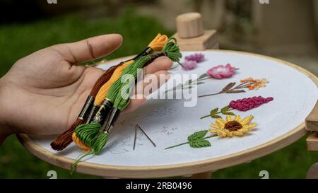 Bestickte Seidenfäden und genähte Blumen auf einem Standbügel Stockfoto