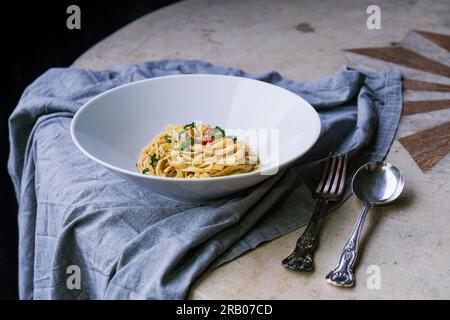 Rustikale Linguine Pasta. Löffel und Gabel mit Stoffserviette. Auf dem Marmortisch Stockfoto