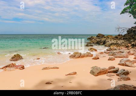 Tropischer Sandstrand mit felsigem Wasser und klarem, blauem Wasser Stockfoto