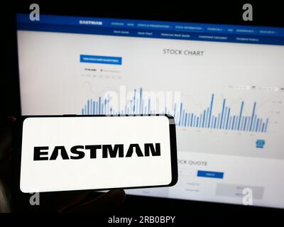 Person, die ein Mobiltelefon mit dem Logo des amerikanischen Unternehmens Eastman Chemical Company auf dem Bildschirm vor der Webseite hält. Konzentrieren Sie sich auf das Display des Telefons. Stockfoto