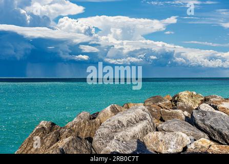 Küste mit Wellenbrecher oder Groyne aus riesigen Felsbrocken und wunderschöne Meereslandschaft mit Sturmwolken (Cumulonimbus) und sintflutartigem Regen. Mittelmeer. Stockfoto