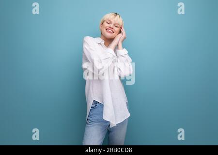 Junge, witzige, weiße blonde Sekretärin in einem weißen Hemd lacht auf dem Hintergrund mit Kopierraum. Das Konzept des Lebensstils der Menschen Stockfoto