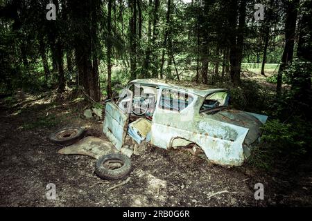 Oldtimer auf einem Autofriedhof in einem Wald Stockfoto