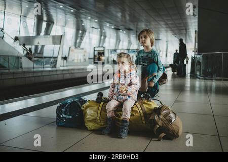 Kinder, die auf dem Gepäck am Bahnhof sitzen Stockfoto