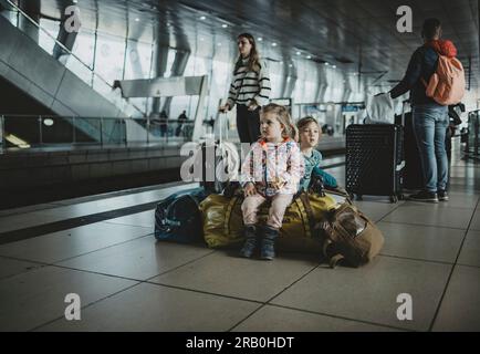 Kinder, die auf dem Gepäck am Bahnhof sitzen Stockfoto