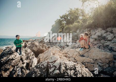 Ein Junge, der mit einem Netz am Festlandufer steht Stockfoto