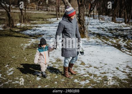 Mutter und Tochter gehen Hand in Hand über die verschneite Wiese Stockfoto