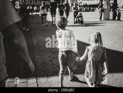 Bruder und Schwester gehen Hand in Hand durch ein Messegelände Stockfoto