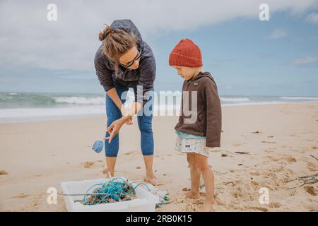 Mutter und Sohn sammeln Müll am Strand Stockfoto