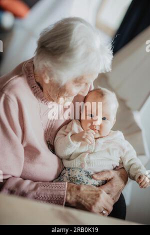 Urgroßmutter hält ihre Urenkelin in den Armen Stockfoto