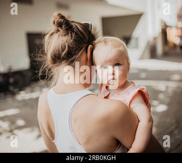 Mutter trägt die Tochter in ihren Armen Stockfoto
