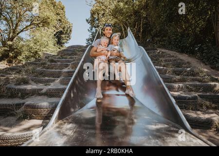 Vater rutscht mit seinen Kindern eine Rutsche hinunter Stockfoto